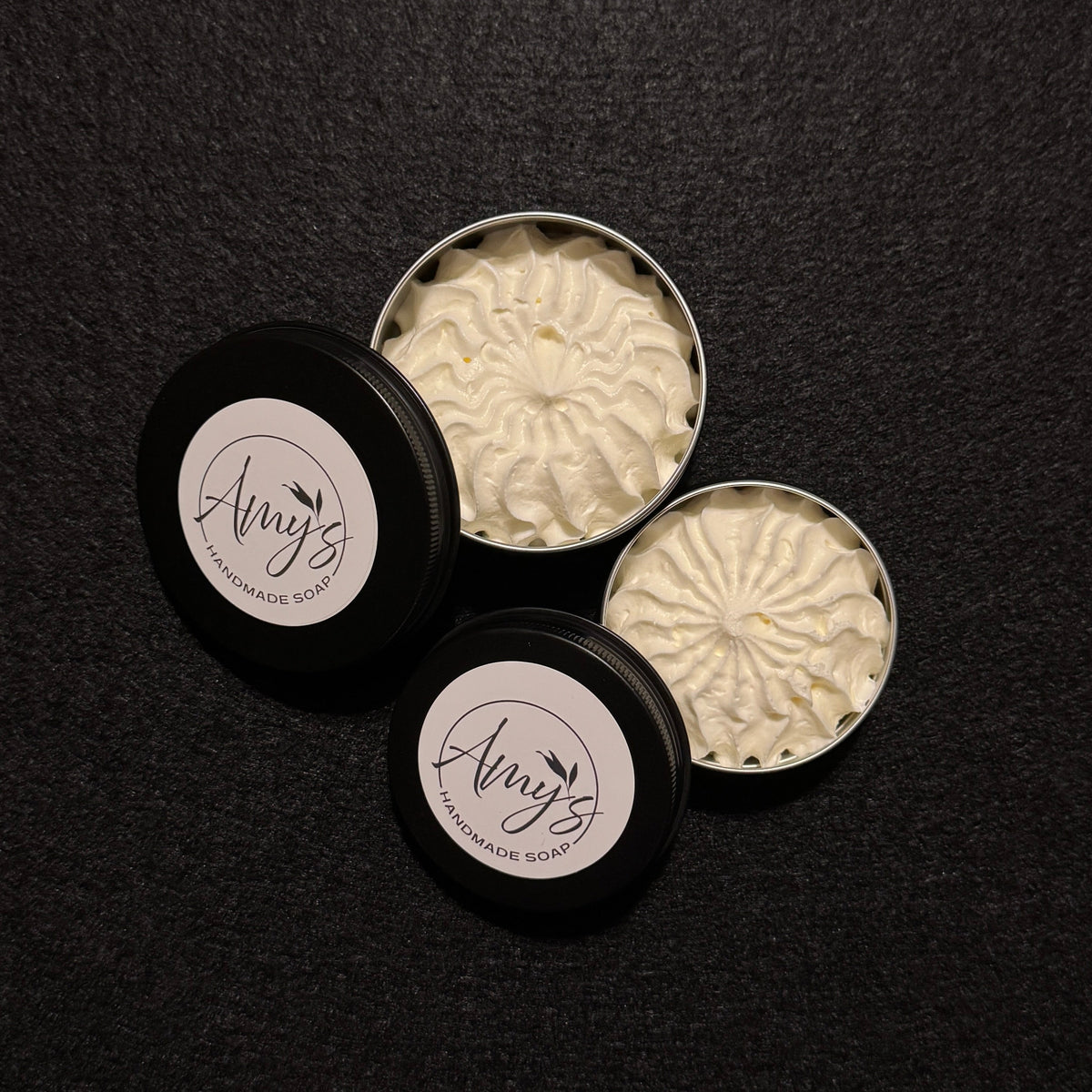 2 black tins filled with spiraling white fluffy cream