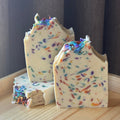 Three bars of soap with colorful sprinkles on a wooden surface