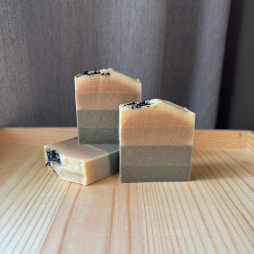 Three layered soap bars on a wooden surface with a neutral background