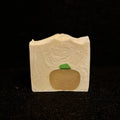 a white square soap with an orange pumpkin embed and a green stem.