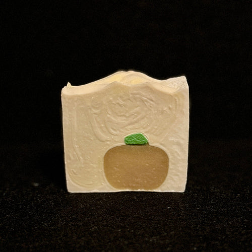 a white square soap with an orange pumpkin embed and a green stem.