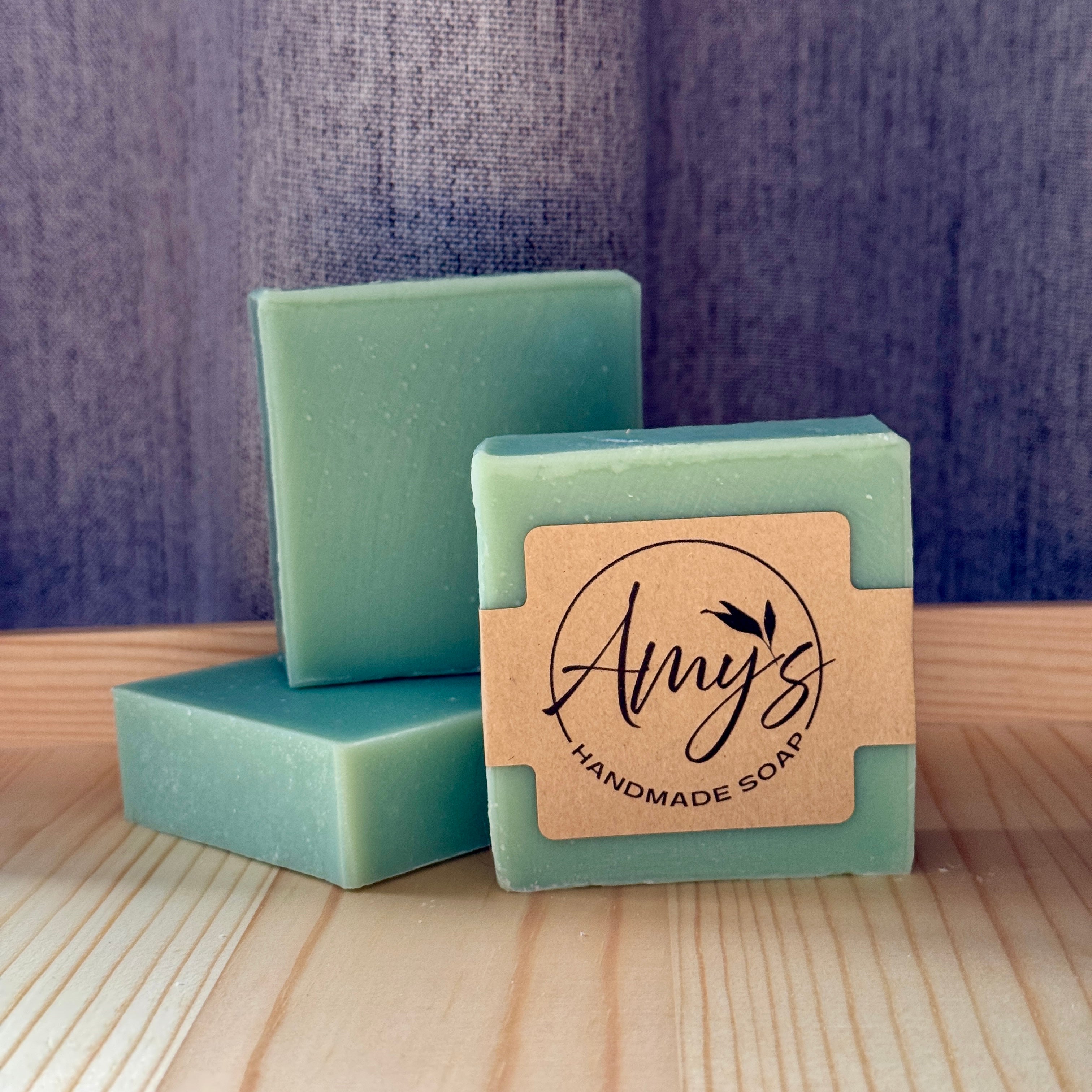 Three bars of green soap with a 'Amy's Handmade Soap' label on a wooden surface.