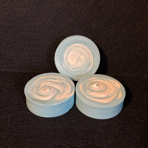 Three small round swirled items in pale blue and white, arranged on a dark textured background.