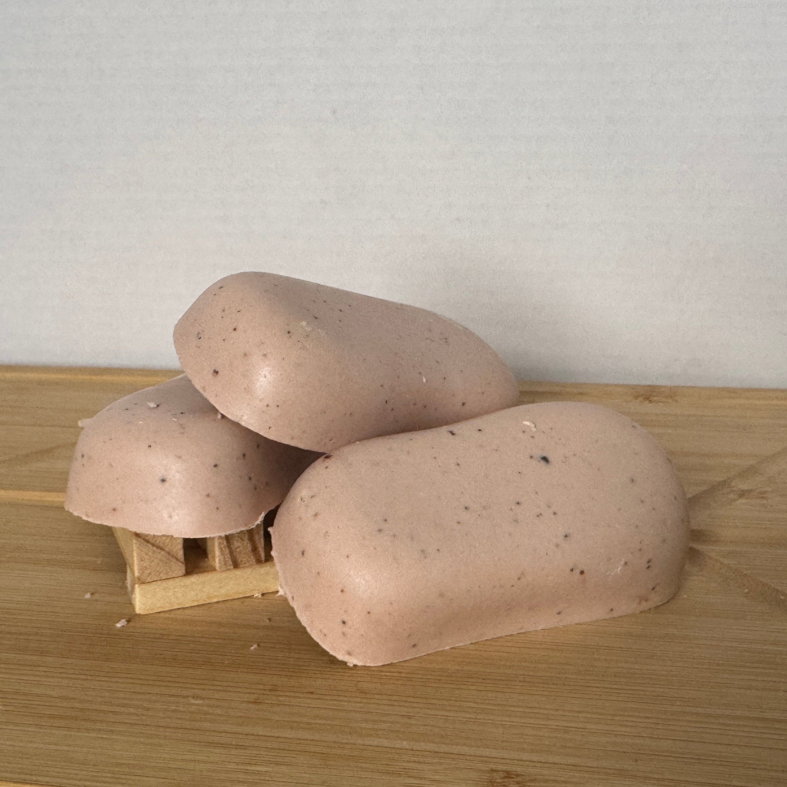 three soaps on a wood surface that look like sand.