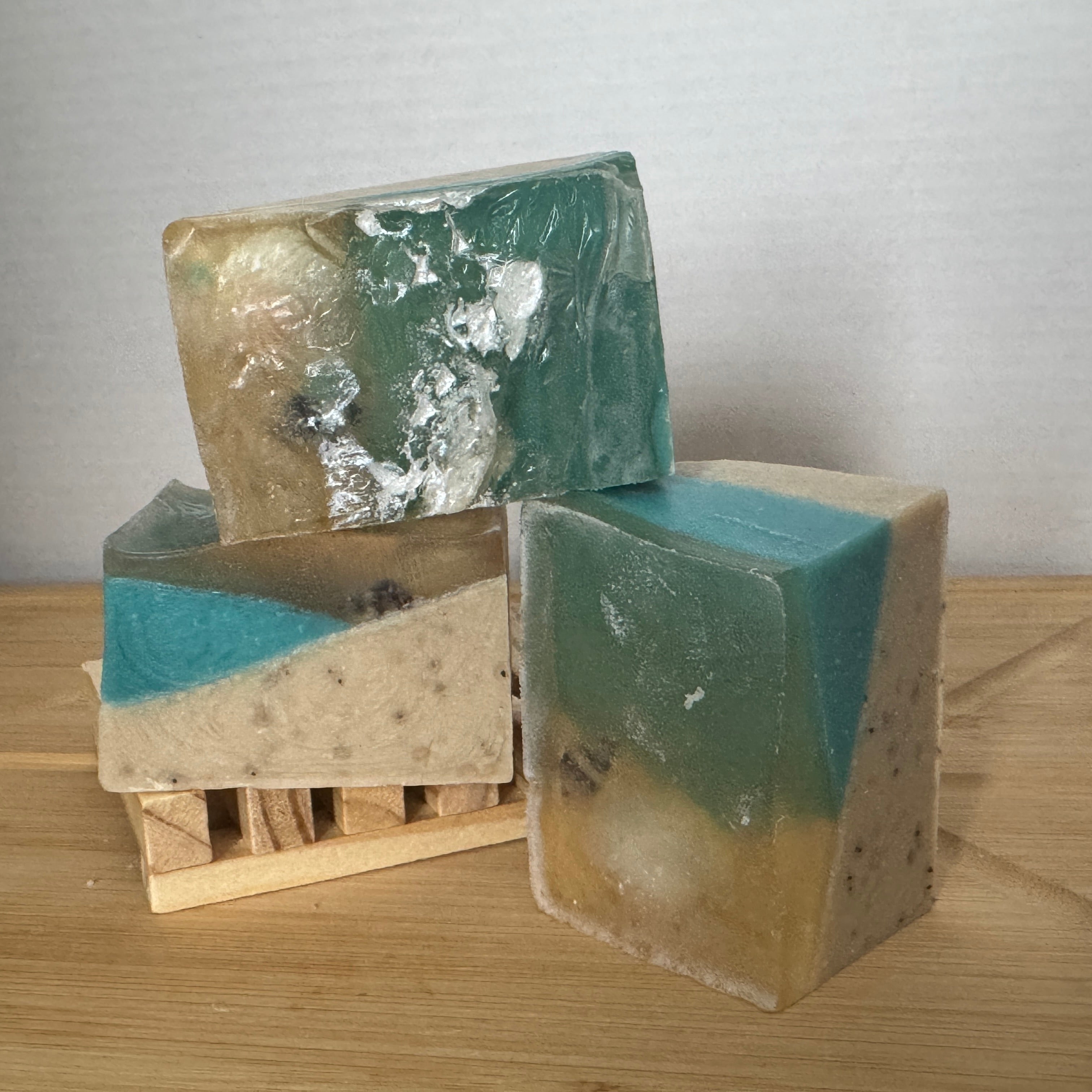 Three layered soap bars with shells on a wooden surface with a neutral background