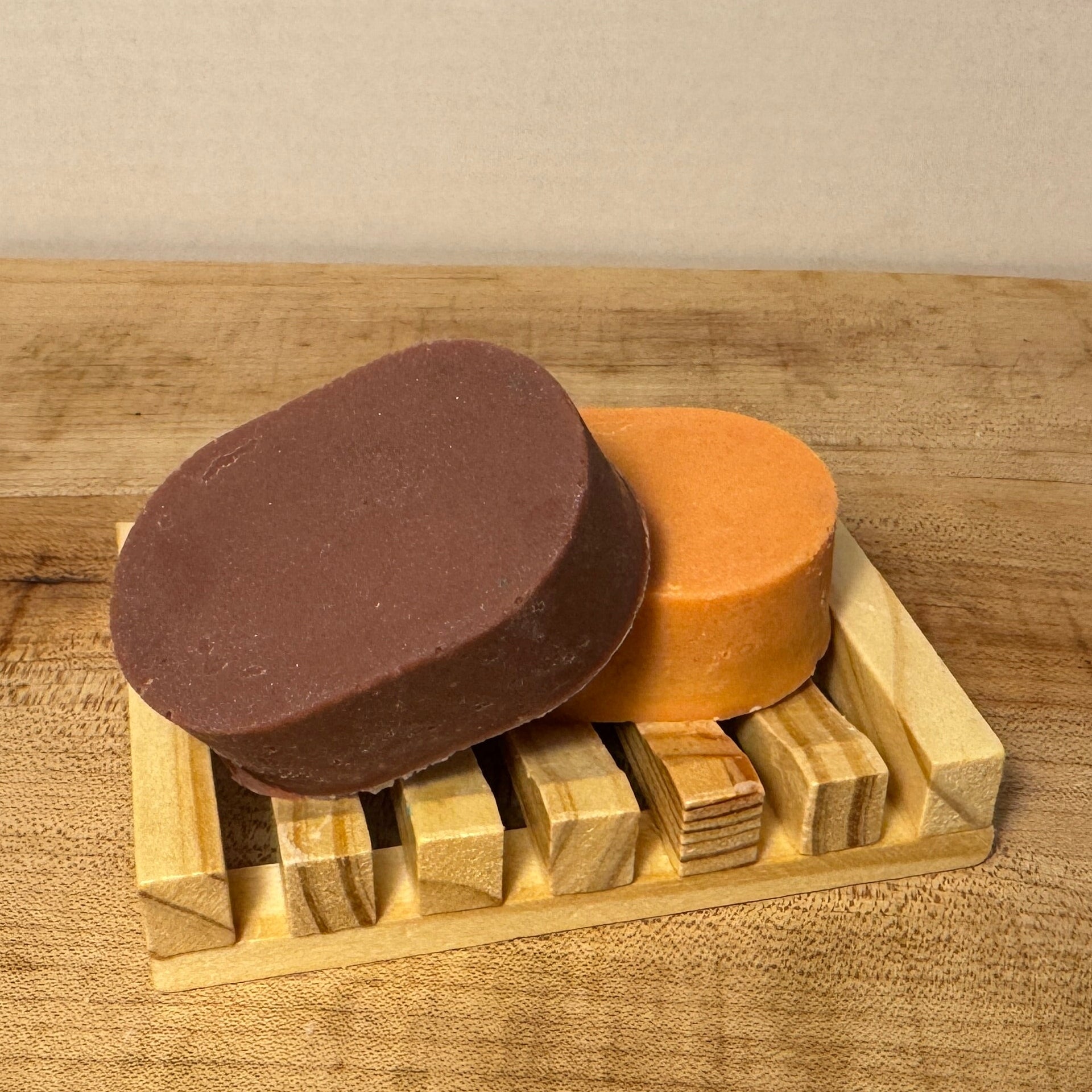 two soaps brown and orange on a wooden soap tray