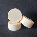 Three round, off-white solid bars stacked and leaning against each other on a dark textured background.