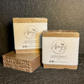Three handmade soap bars wrapped in kraft paper bands with the brand name 'Amy's Handmade Soap' printed on them, displayed on a dark textured background.
