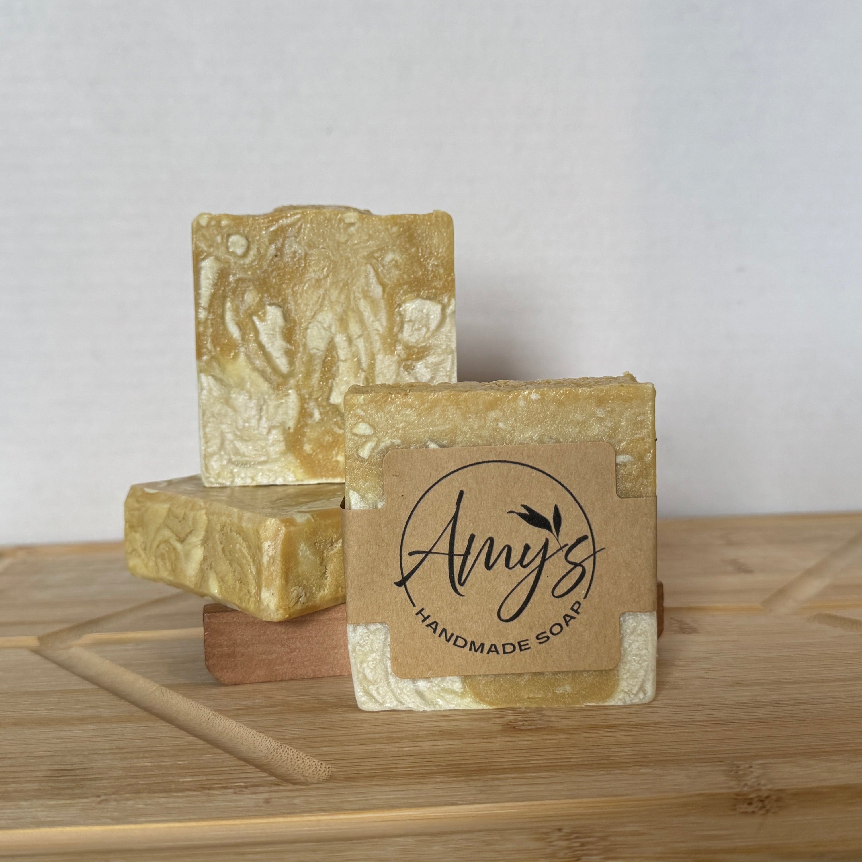 Three bars of soap with 'Amy's Handmade Soap' branding on a wooden surface.