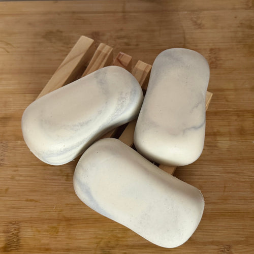 3 white and grey bars of soap on a wooden board.