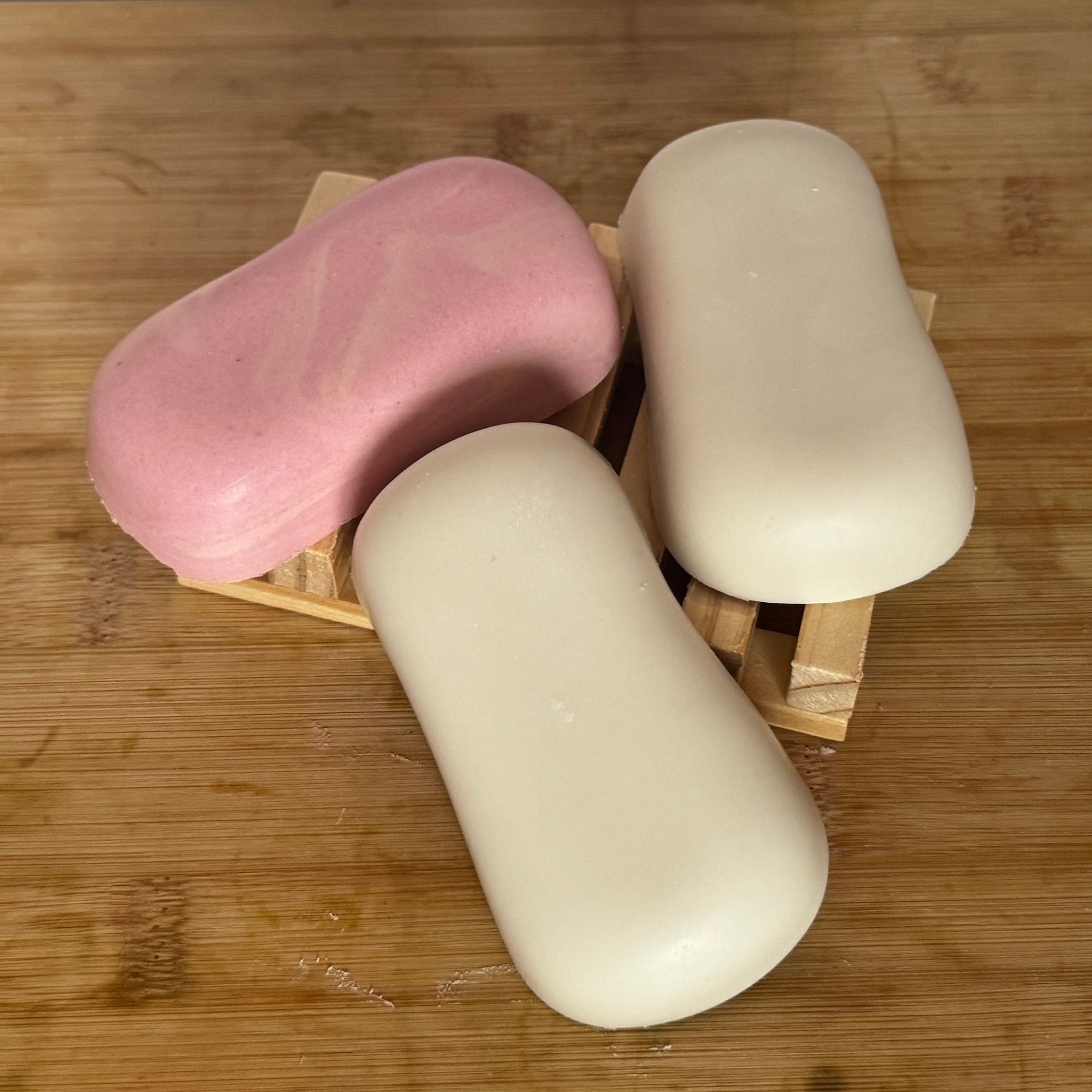 3 bars of soap 2 white 1 pink on wooden board