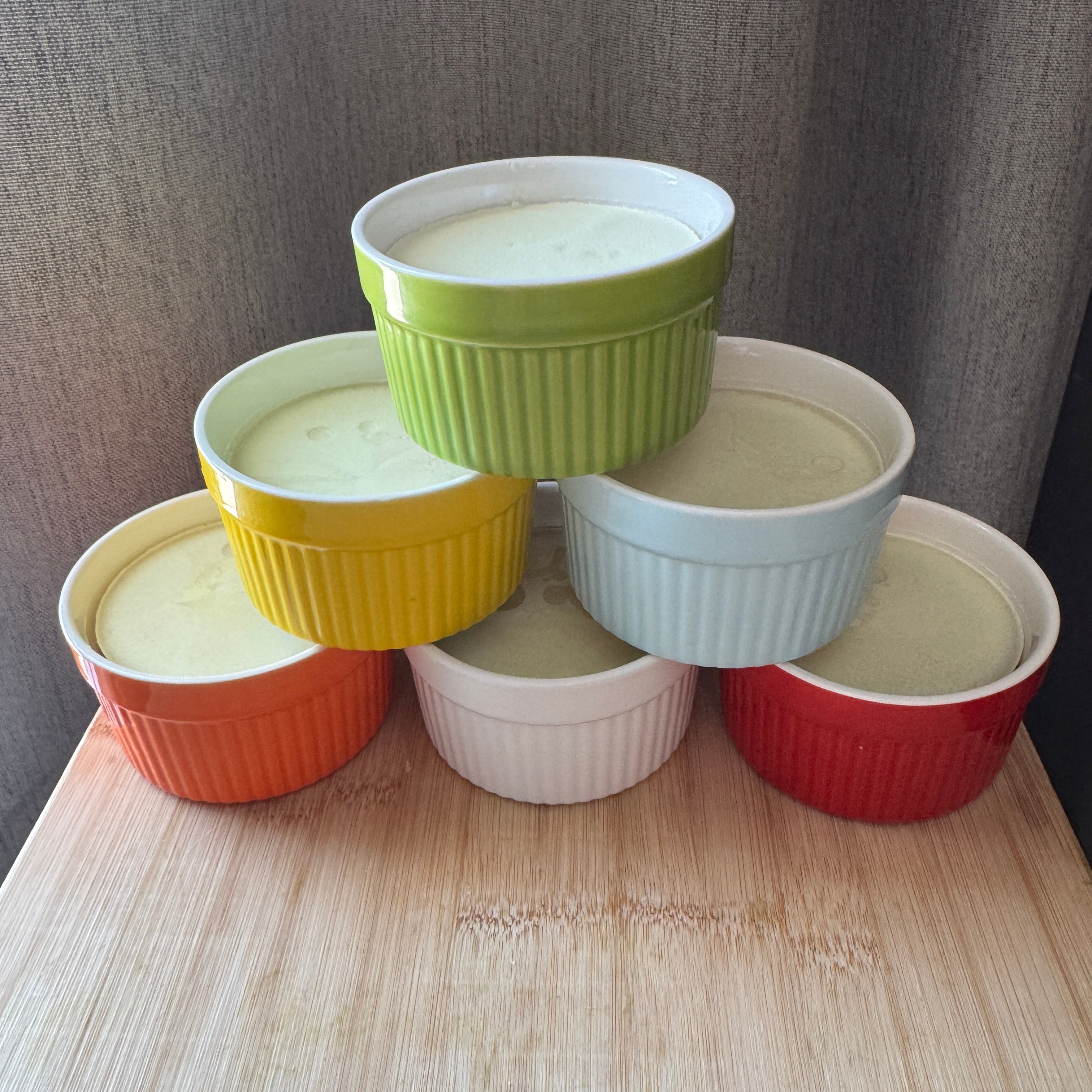 Stack of colorful ramekins on a wooden surface with a neutral background