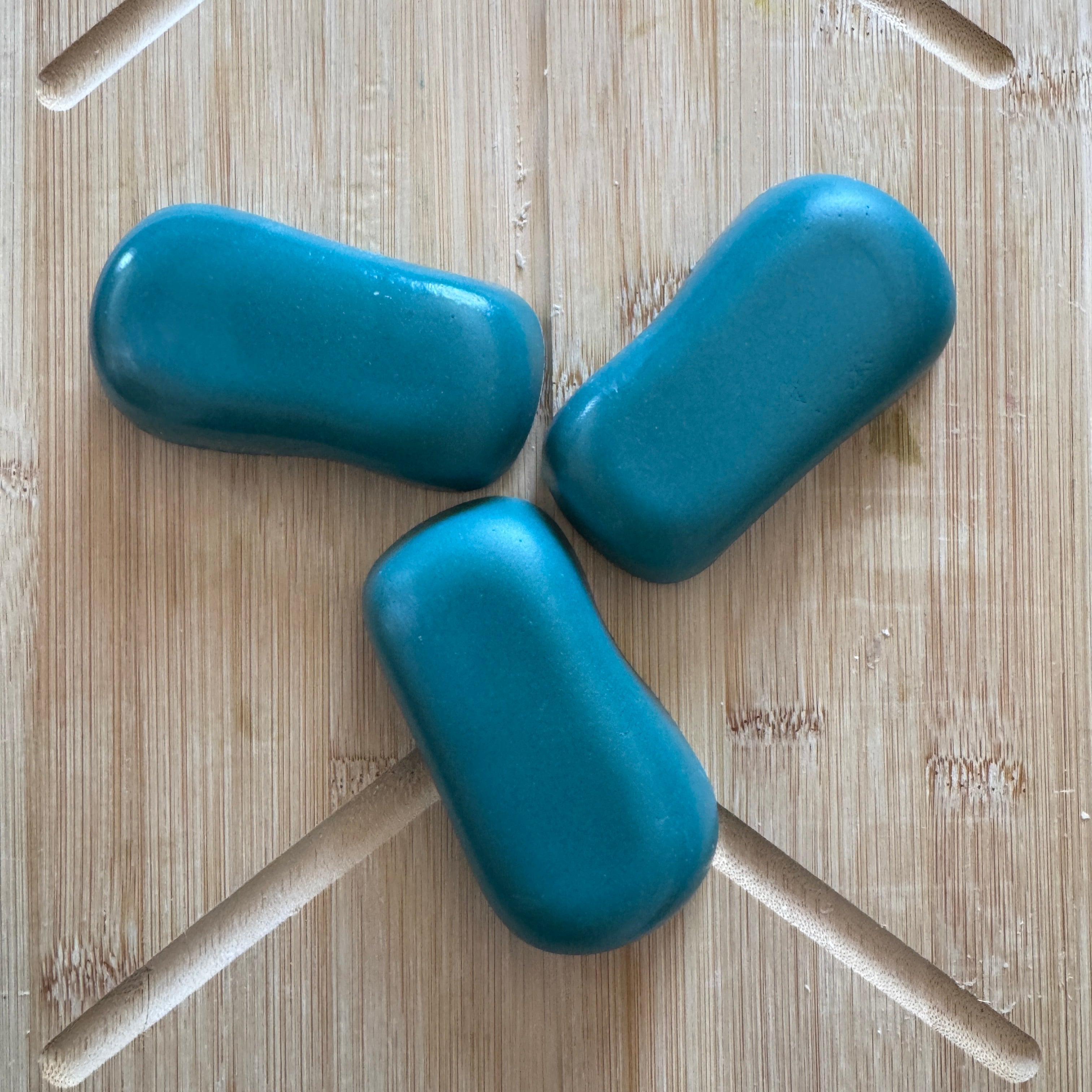 3 green blue soaps on a wooden board