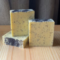 3 light yellow soaps sprinkled with poppyseeds on a wooden surface