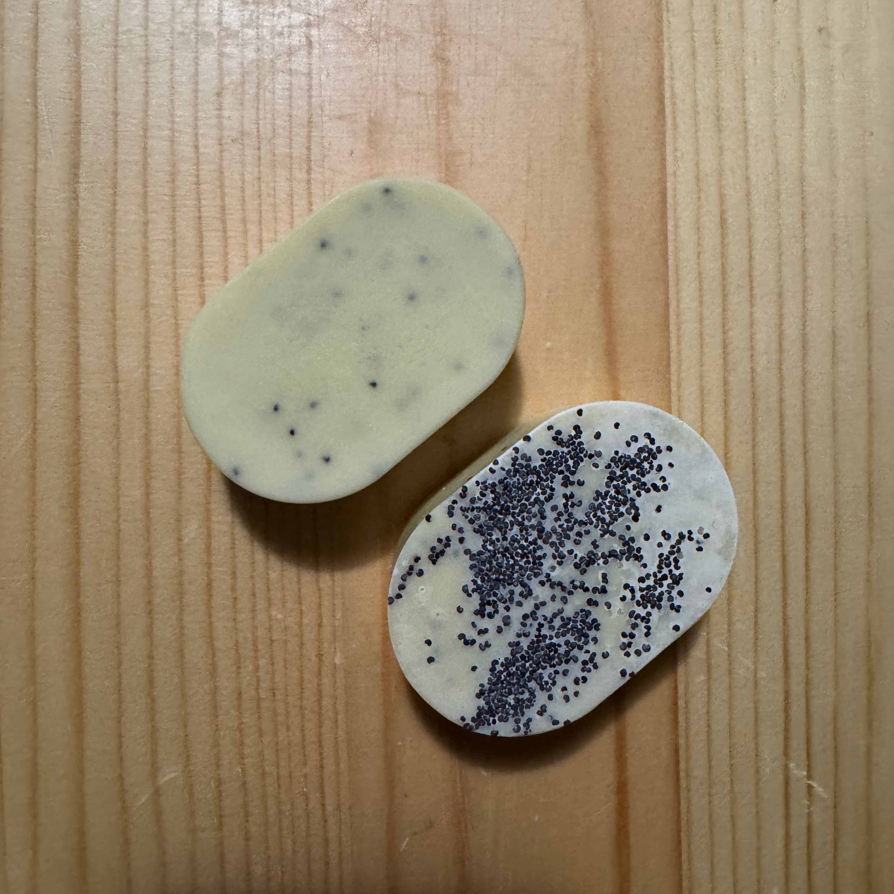 2 oval yellow soaps on a wooden surface