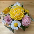 Bouquet of yellow, pink, and white flowers on a wooden surface