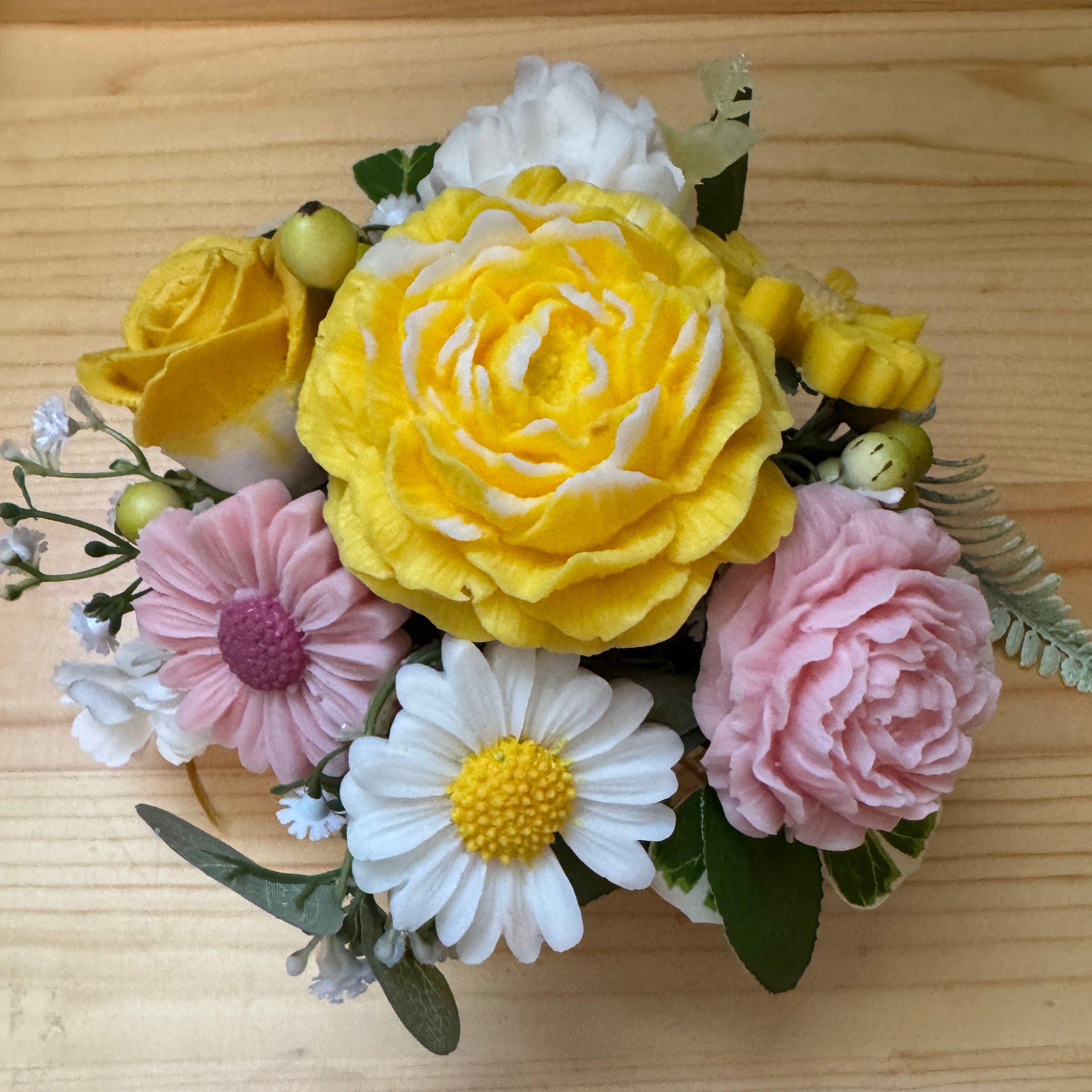 Bouquet of yellow, pink, and white flowers on a wooden surface