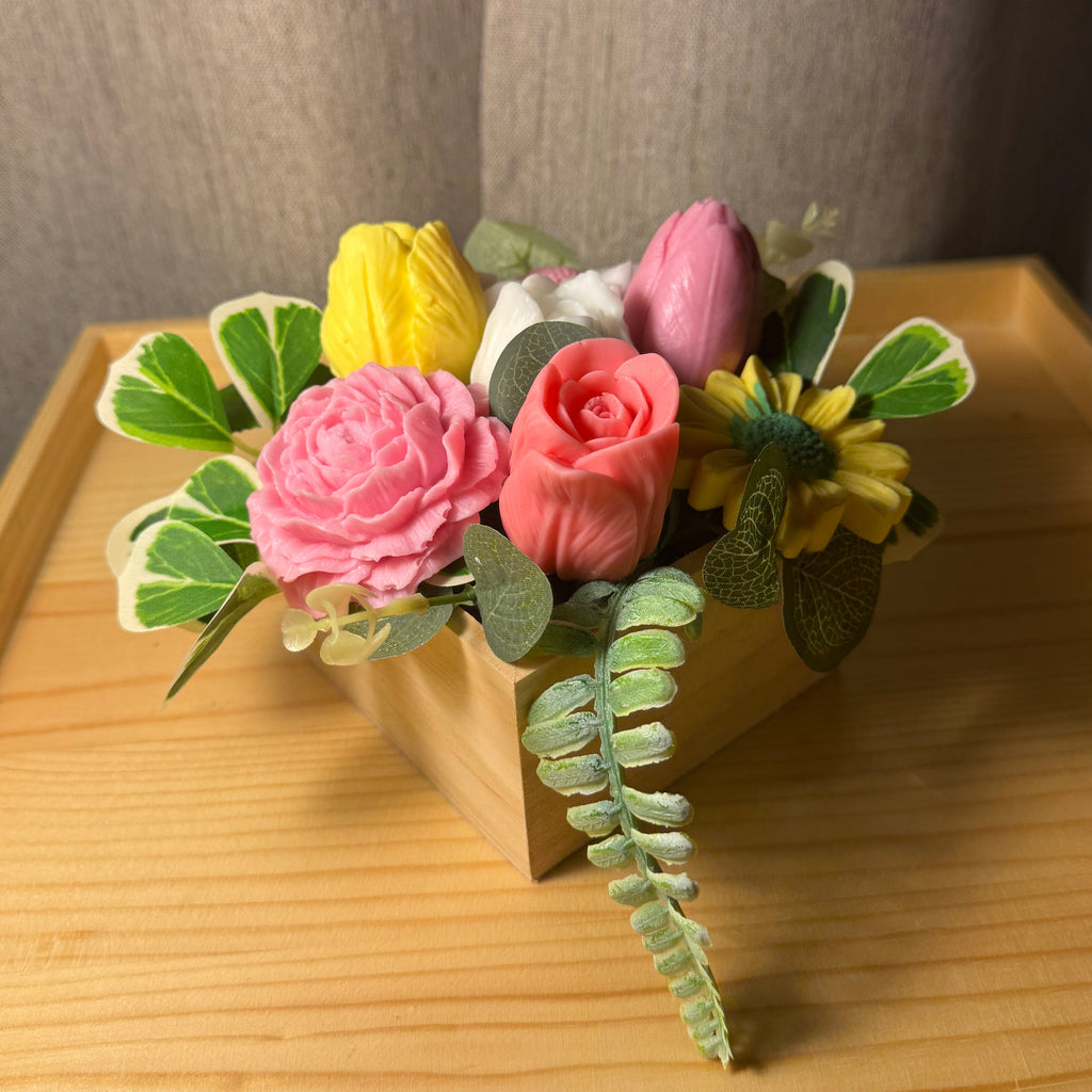 Artificial flower arrangement in a small pot on a wooden surface