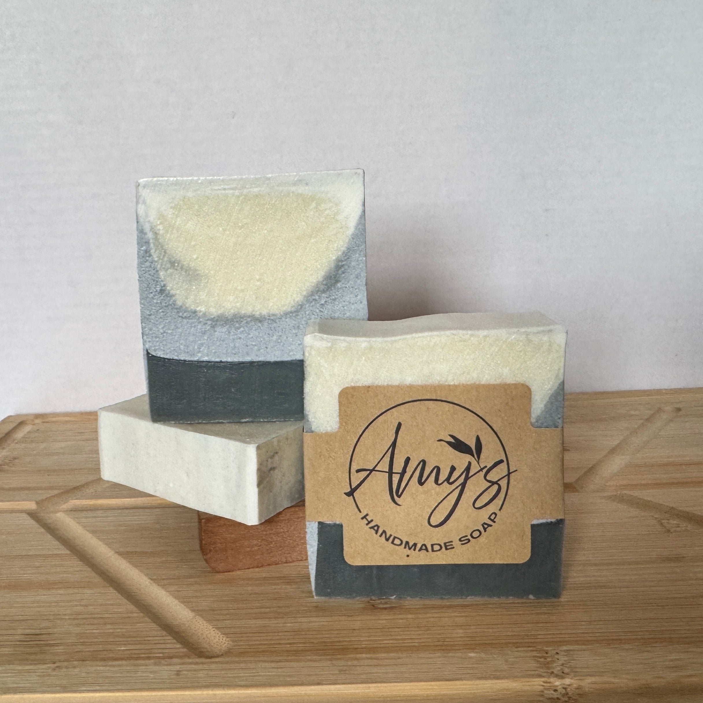 Two handmade soap bars on a wooden surface with a plain background