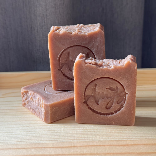 Three bars of soap with a brand logo on a wooden surface