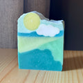 Bar of soap with a sun and cloud design on a wooden surface