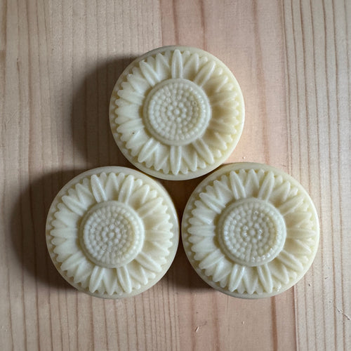 3 floral shaped soaps on a wooden board