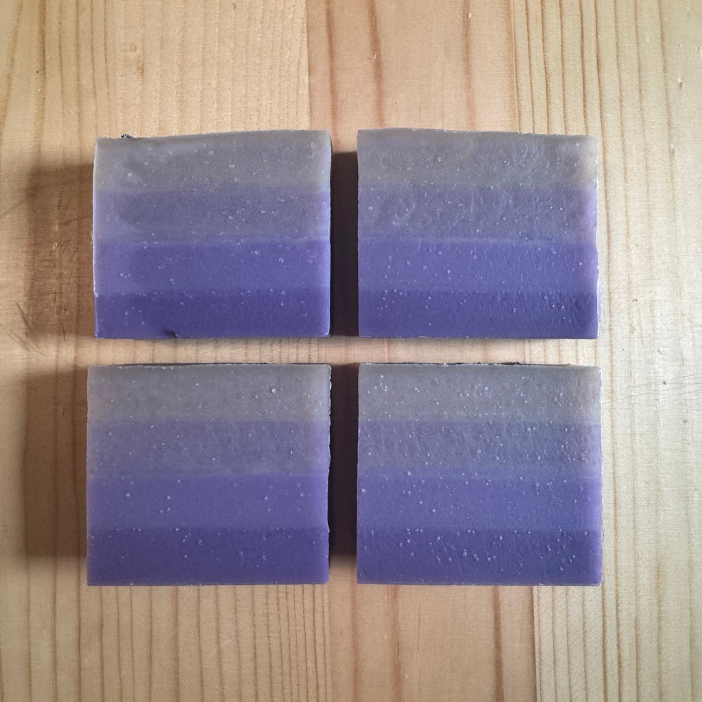 Four rectangular purple soap bars on a wooden surface