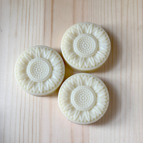 Three white textured soap bars on a light wooden surface