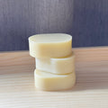 Stack of three cylindrical soap bars on a wooden surface with a neutral background