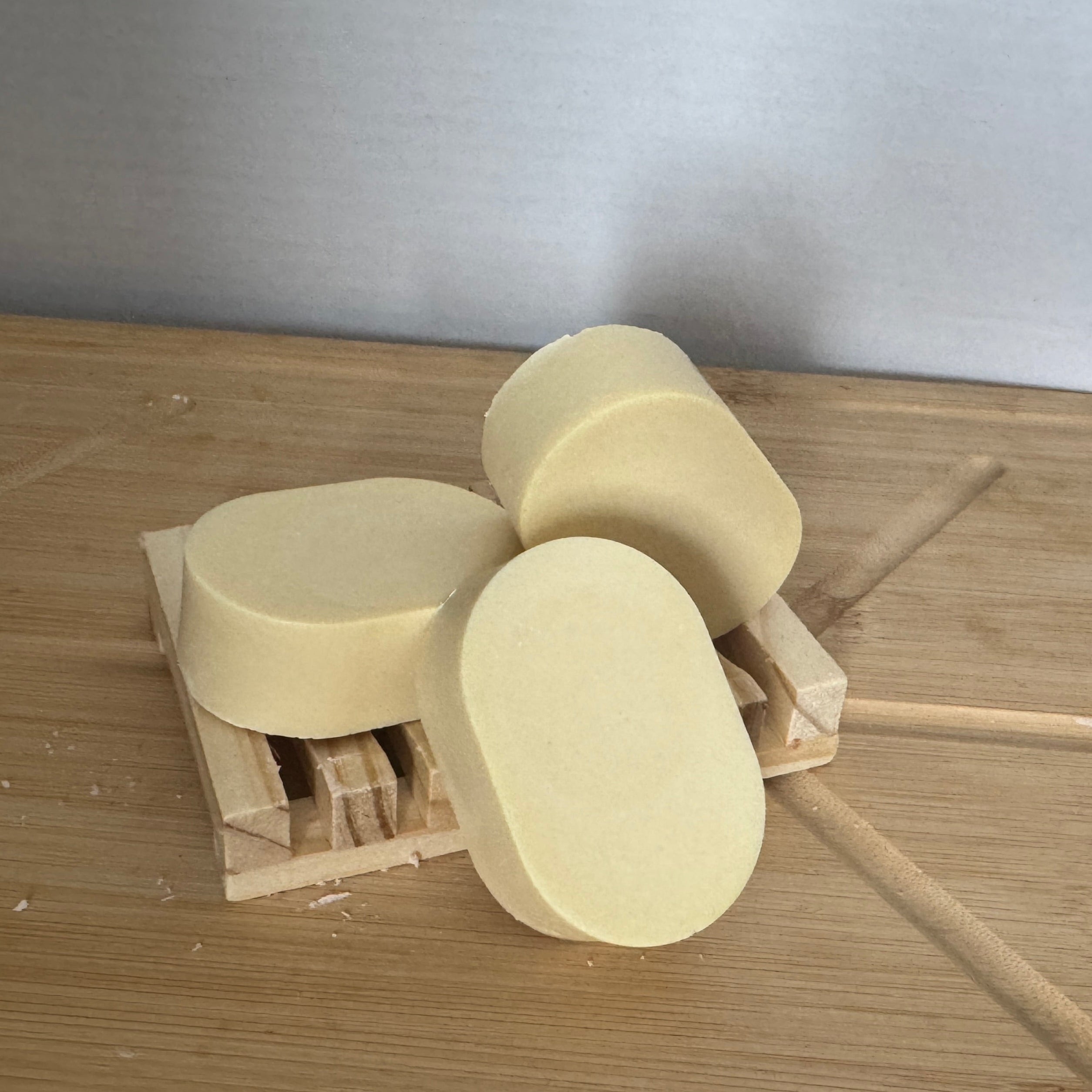 three oval shaped light yellow soap bars on a wooden surface