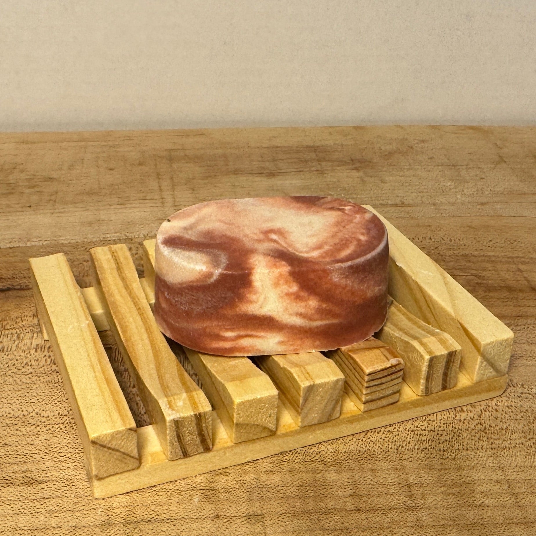 an oval red and white swirl soap on a wooden soap tray