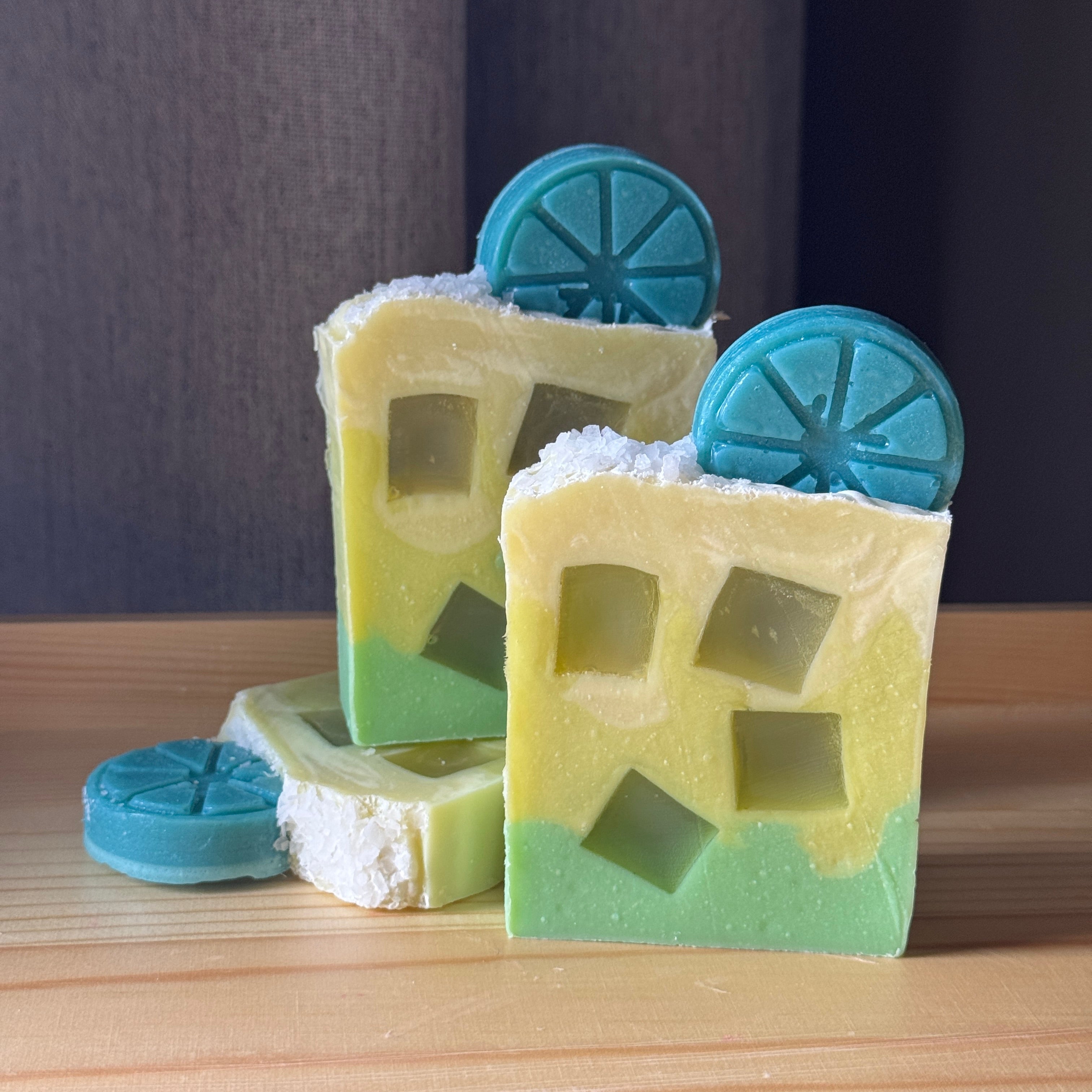 Three bars of soap with window-like cutouts and blue circular shapes on a wooden surface.