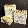Three handmade soap bars wrapped in white paper labels reading Amy's Handmade Soap, arranged on a dark textured background. The soaps are pale green with chocolate shavings and topped with dark chocolate shavings.