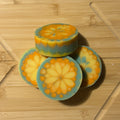 Three decorative soaps with floral patterns on a wooden cutting board.