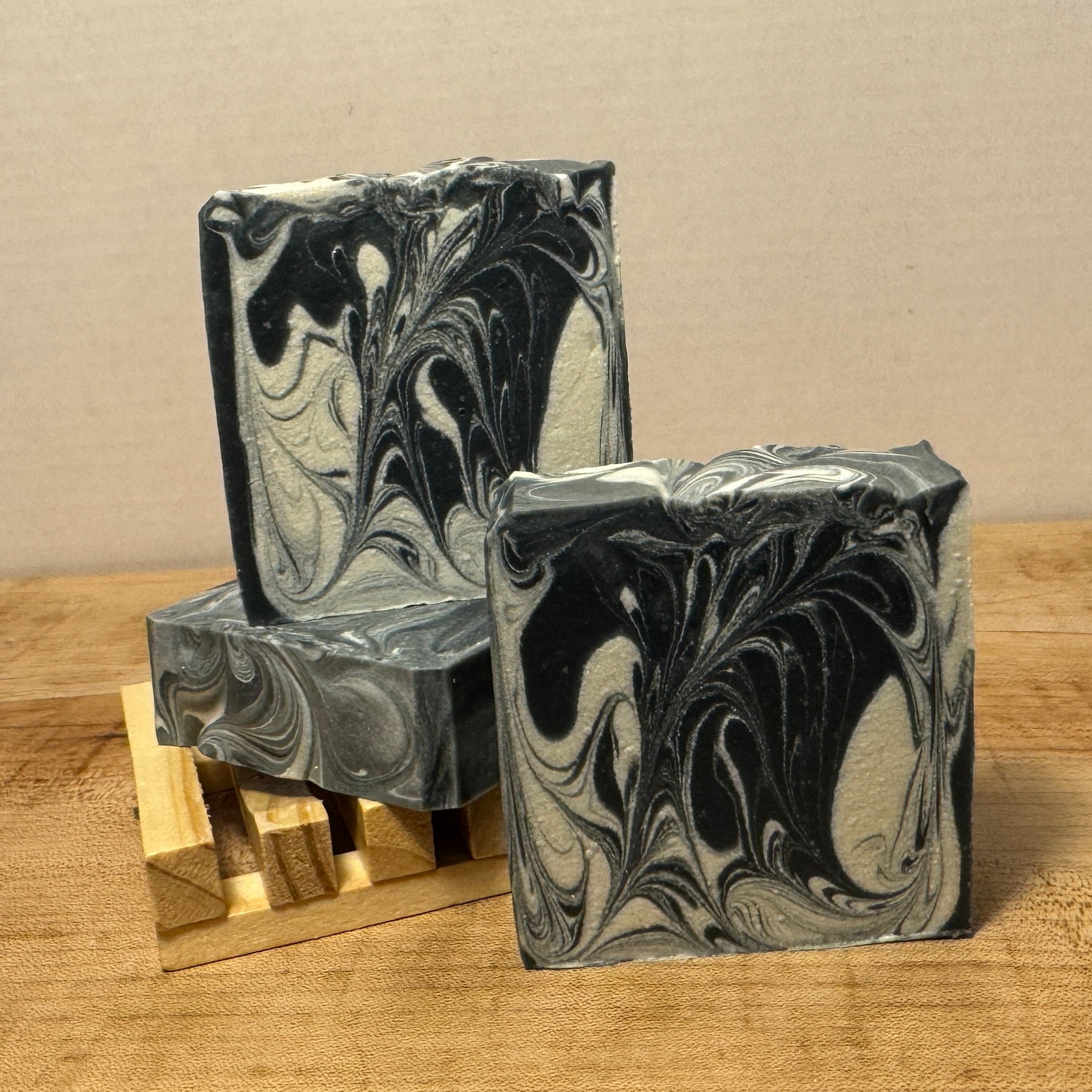Two marbled soap bars on a wooden surface with a neutral background