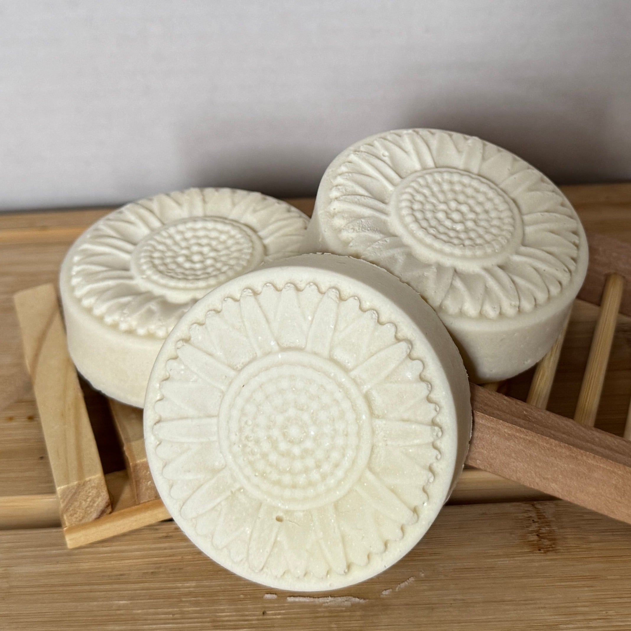 3 round bars of white soap on a wooden board