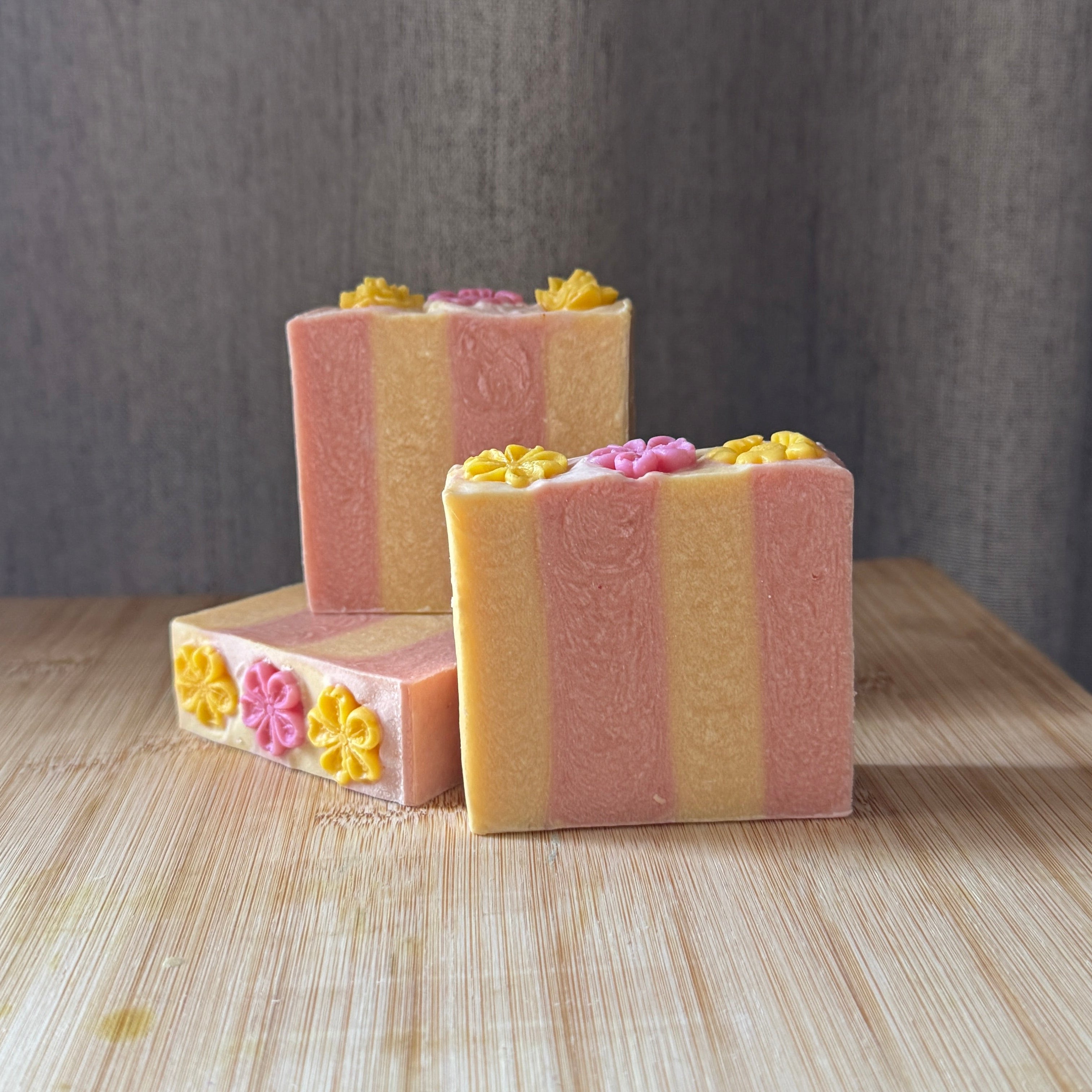 bar of soap with pink and yellow vertical stripes yellow and pink flowers on top