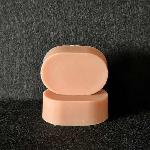 2 ovals of light pink soap stacked on a black felt surface