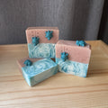 Three bars of soap with marbled design and turtle figurines on a wooden surface.