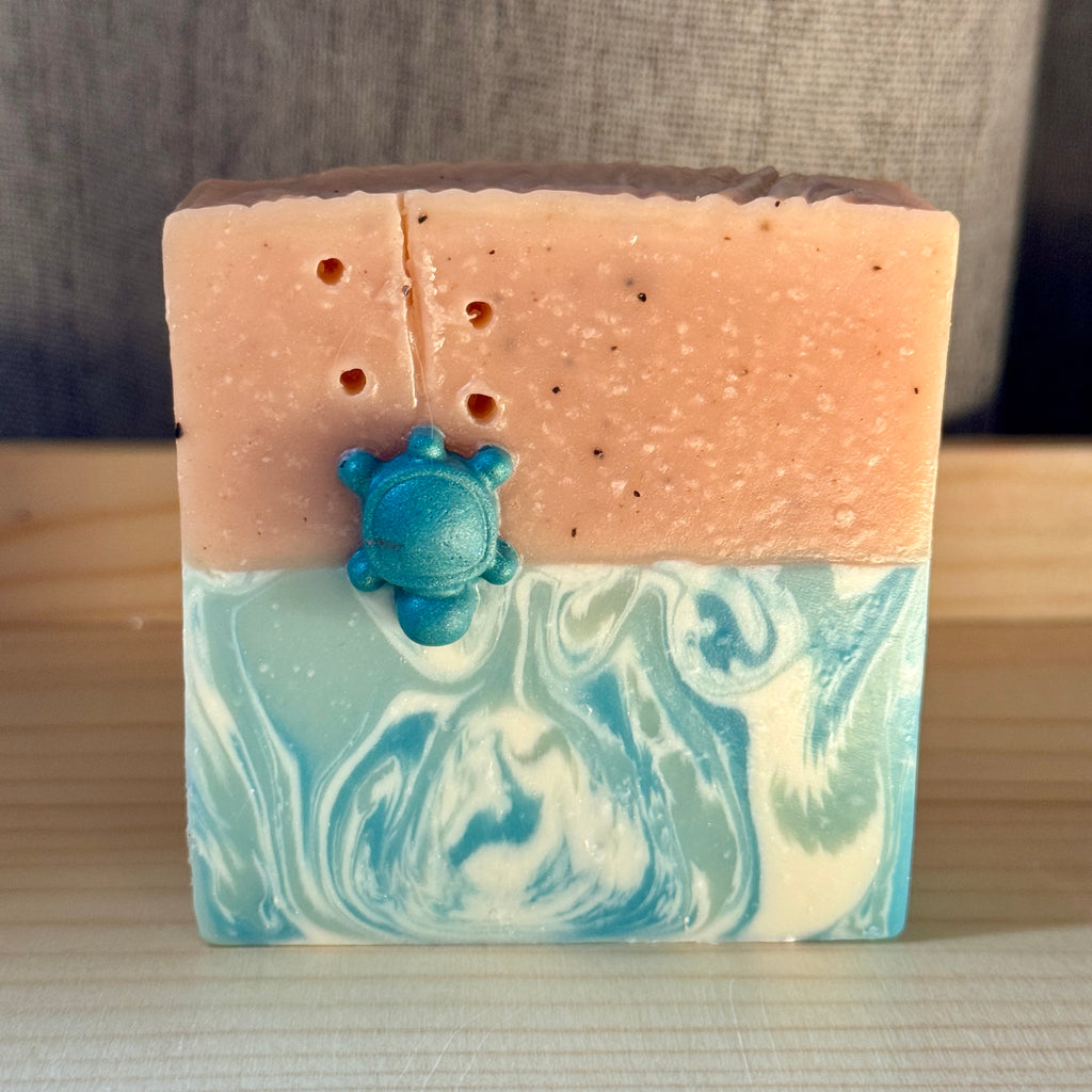 Bar of soap with a turtle charm on a wooden surface