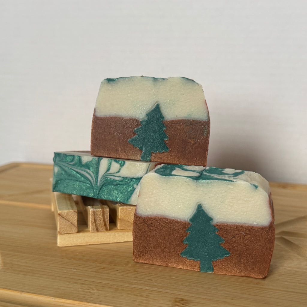 Three soap bars with tree designs on a wooden surface