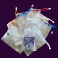 White drawstring bags with colorful tags on a wooden board