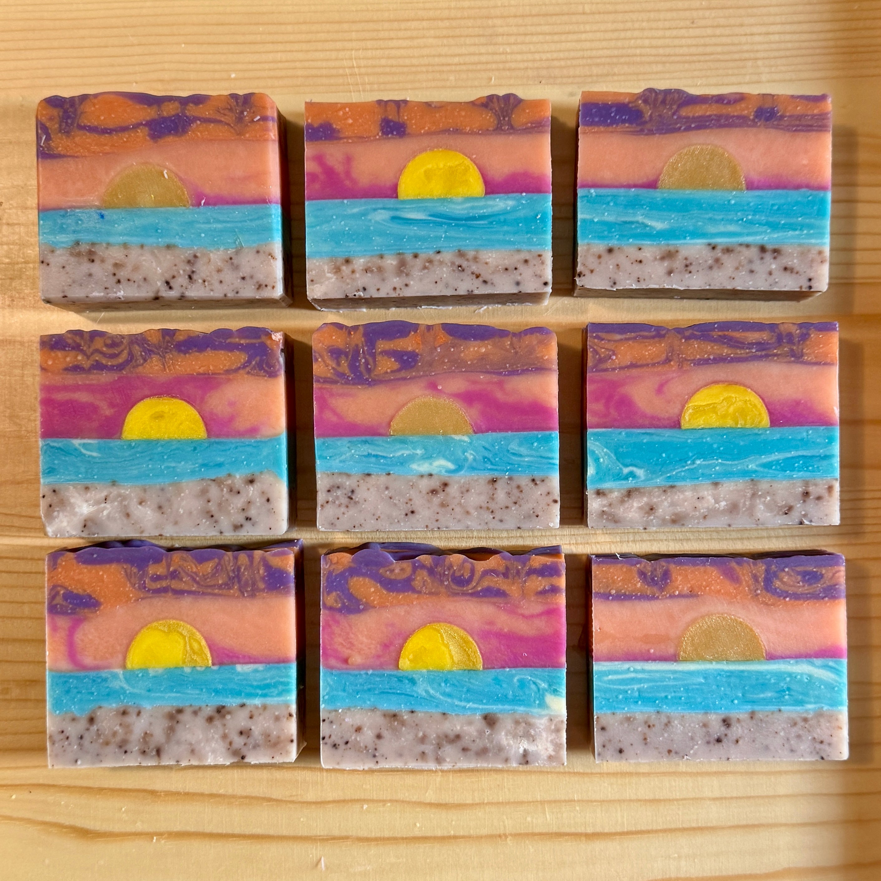Nine soap bars with sunset design on a wooden surface