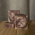 Three marbled soap bars on a wooden surface with a neutral background