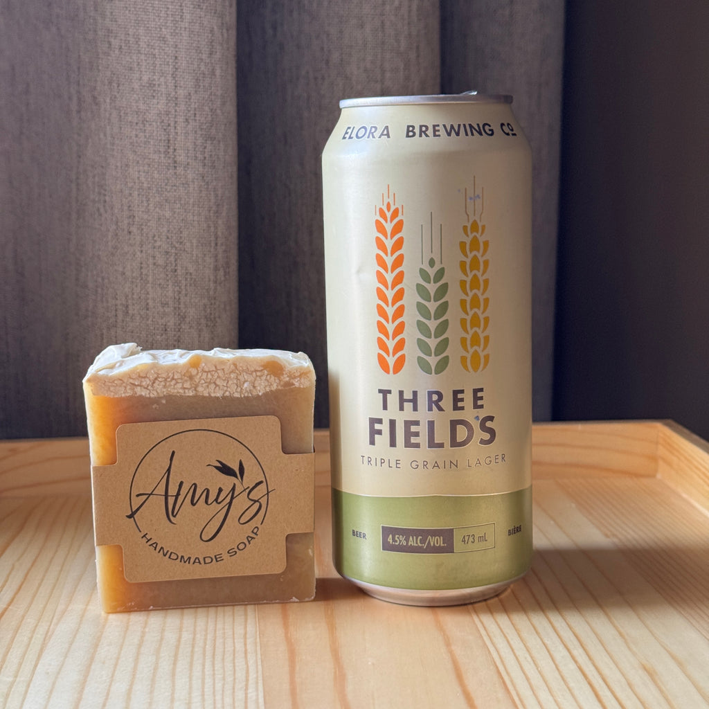 Can of Three Fields beer and a bar of Amy's Handmade Soap on a wooden surface.