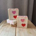 Three bars of soap with heart designs on a wooden surface