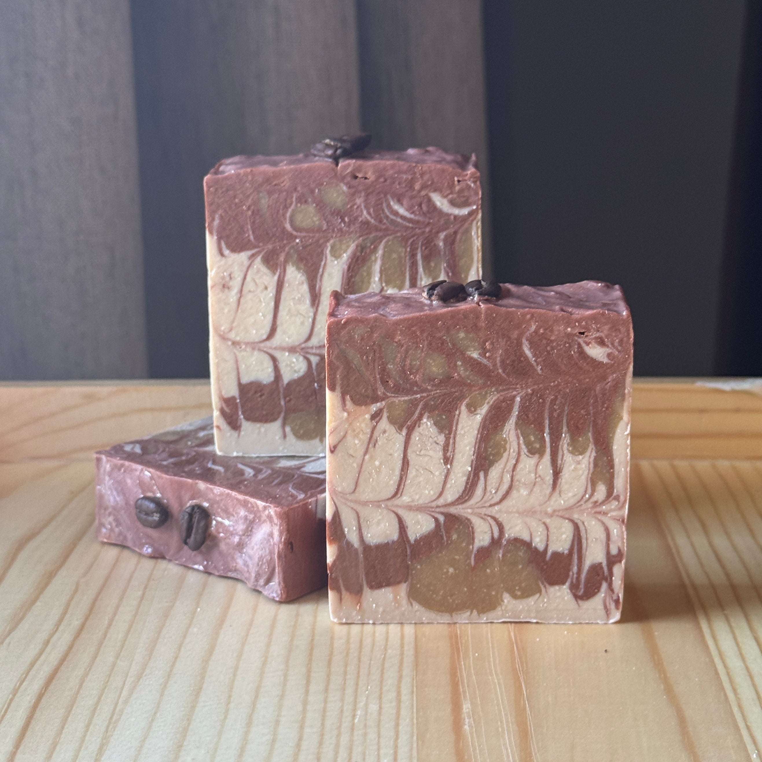 Three bars of soap with a marbled pattern on a wooden surface