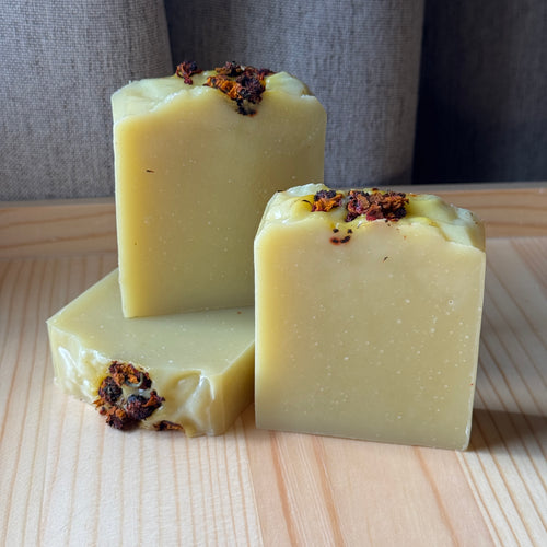 3 light yellow soaps with dried flowers on a wooden board